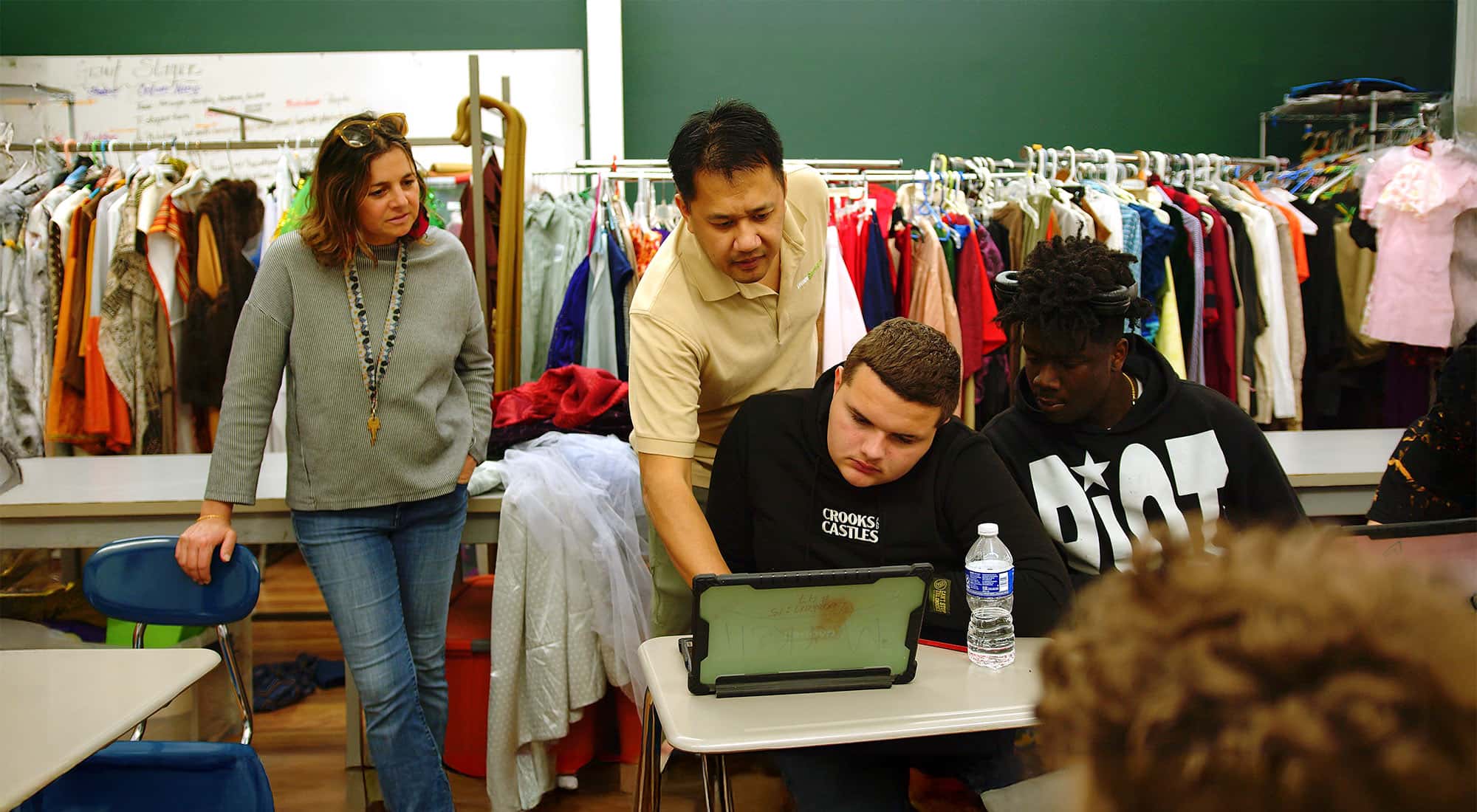 Instructor and students reviewing work together on a laptop
